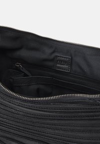 Schwarze Leder-Clutch-Tasche Innenansicht, die eine Reißverschlusstasche, eine Einschubtasche und eine horizontal gerüschte Textur mit glattem Futter aufweist.