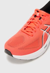 Bright coral running shoe with a mesh upper, black and white accents, and textured sole. Features lacing system and FFBlast branding.