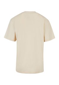 Tricou bej cu mânecă scurtă, realizat din bumbac moale, având un gât clasic rotund și o textură simplă, netedă, fără modele sau accente.