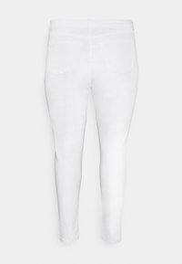 Jeans ajustados blancos con una textura suave, cintura de altura media y dos bolsillos traseros. Diseñados con una forma ajustada y sin detalles de hardware visibles.