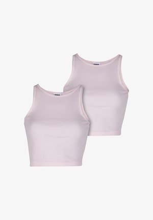 Haut rose clair sans manches et short assorti ; s'arrêtant au-dessus de la taille. Porté avec des chaussettes blanches montantes et des baskets marron et roses. Tient un sac clair.