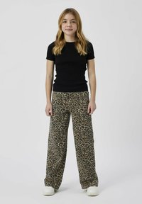 Svart ribbad kortärmad topp i kombination med vida leopardmönstrade byxor. Vita sneakers fulländar outfiten.