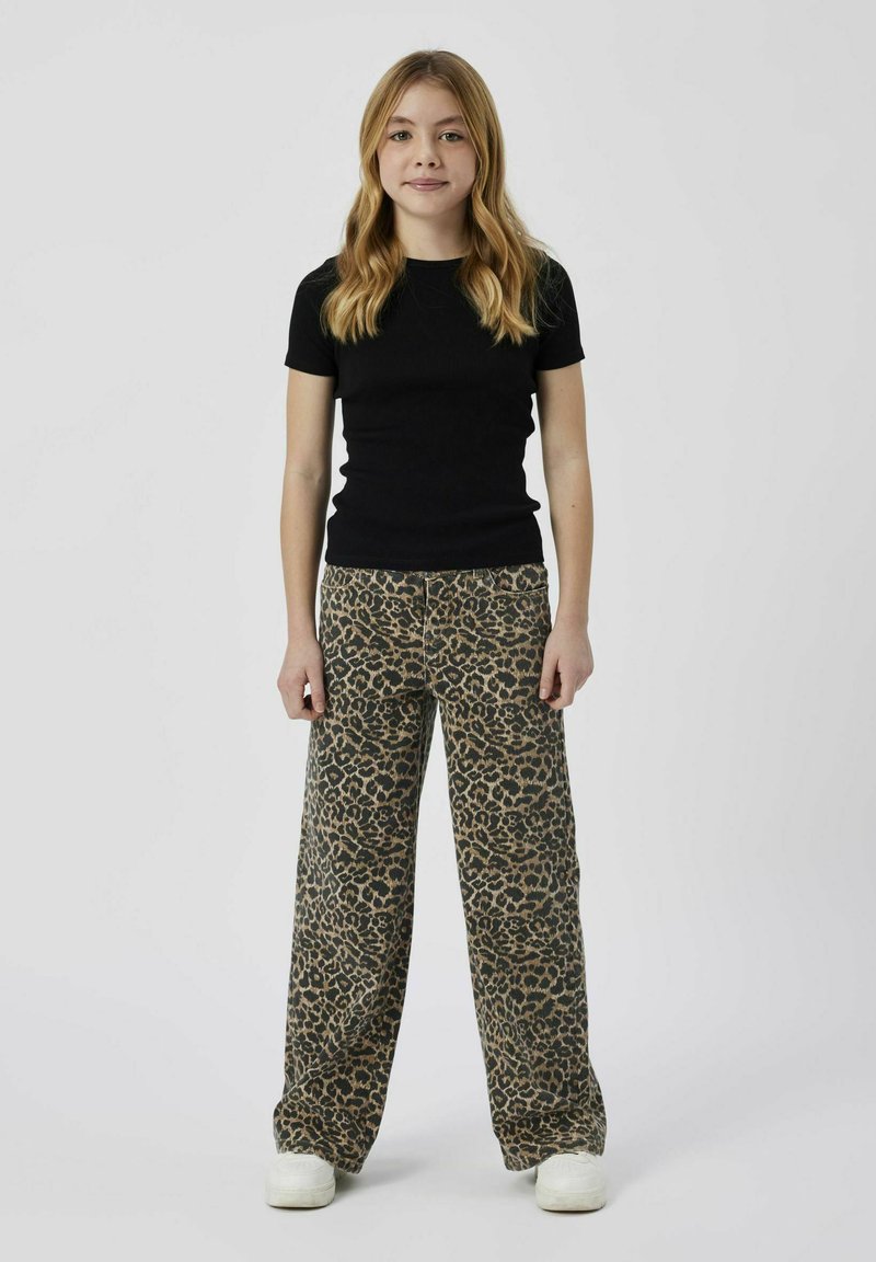 Svart ribbad kortärmad topp i kombination med vida leopardmönstrade byxor. Vita sneakers fulländar outfiten.