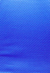 Tecido azul texturizado com um padrão hexagonal. O material parece suave e ligeiramente brilhante, transitando de tons de azul claro para escuro.