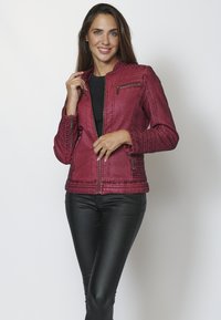 Burgundia faux nahast jakk, millel on tikitud tekstuur, tõmblukuga taskud ja soonikkoes aktsendid õlgadel. Stiliseeritud mustade nappide pükste juurde.