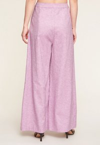 Wide-leg trousers in a light purple, textured fabric. Features a high waist and a relaxed fit, tapered at the ankles with subtle sheen.
