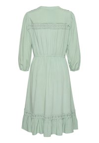 Hellgrünes Midi-Kleid mit dreiviertel langen Puffärmeln, elastischem Bund, Spitzenbesatz entlang der Rückenpasse und dem Saum sowie einem Rüschensaum.