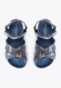 Sandali di jeans con cinghie incrociate, applicazioni metalliche a mano, soletta blu e suola in stile espadrilles color marrone chiaro.