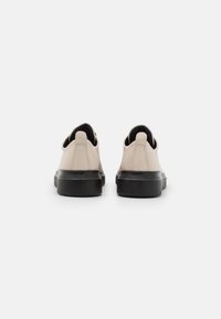 Beige leather shoes with a smooth texture, a rounded shape, and a thick black rubber sole. Features a small back tab for easy wear.