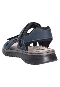 Navy blue sandals with a textured upper, featuring open sides, Velcro straps, and a cushioned sole for comfort. Lightweight design.