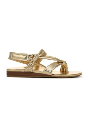 Gouden metalen sandalen met geknoopte bandjes, open teen en een platte houten zool; voorzien van een gladde textuur en verstelbare enkelband.