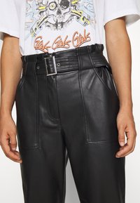 Svarta läderbyxor med hög midja, med ett brett bälte och sidofickor. Materialet har en slät yta och en lätt lyster.