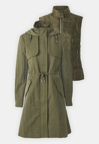 Cappotto convertibile verde oliva con uno strato esterno leggero e un gilet trapuntato. Presenta una vita con cordino, tasche e un cappuccio.