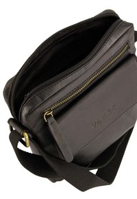 Sort læder crossbody taske med en lynlåslukket hovedrum, justerbar stofrem og prægede "Venezia" logo på forsiden.