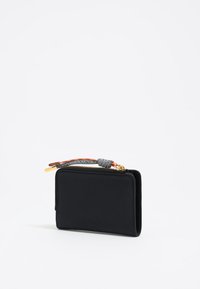 Billetera de cuero negro con un acabado texturizado, forma rectangular, herrajes de cremallera en dorado y plateado, y una correa decorativa con un acento de nudo.