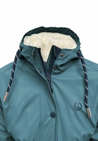Teal waterproof jacket with a furry inner lining, adjustable drawstrings, snap buttons, and a logo detail on the front.