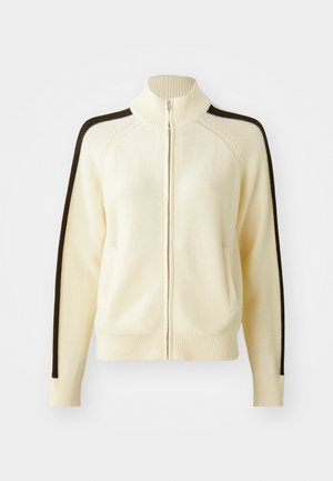 Cream zipper cardigan with a high collar, featuring dark brown side stripes, ribbed cuffs, and two front pockets. Knitted texture.