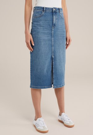 Falda midi de mezclilla en azul claro con una abertura frontal, diseño de cinco bolsillos y presillas para cinturón, combinada con zapatillas blancas y grises.