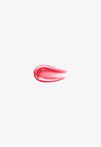Trace brillante de gloss à lèvres rouge avec des reflets lumineux scintillants sur un fond blanc uni.