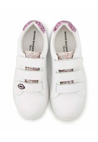 Witte sneakers met drie klittenbandsluitingen, voorzien van roze en zilveren glitters op de hiel en een zwarte lipgraphic aan de zijkant.