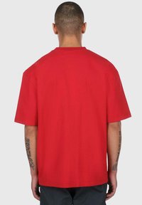 Rød kortærmet T-shirt lavet af bomuld. Har en afslappet pasform med lige kant og simpel halsudskæring. Ingen synlig branding eller mønstre.