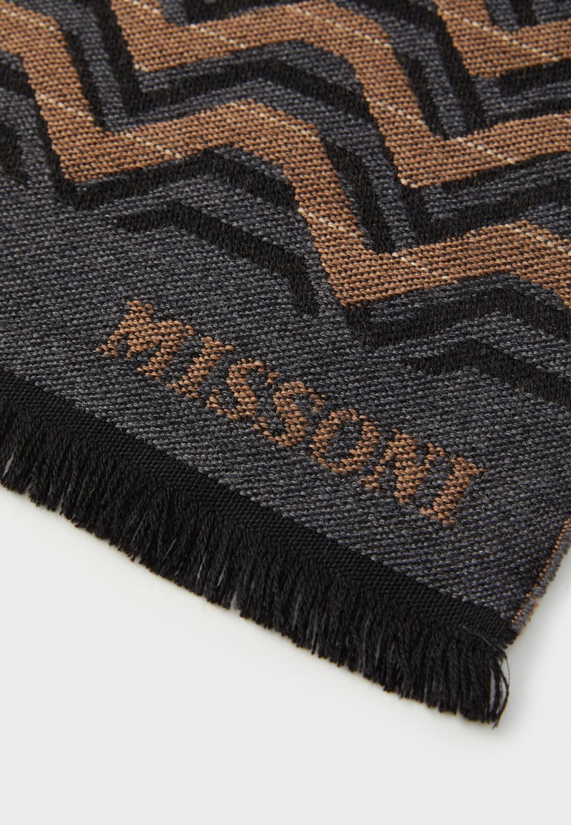 Tessuto intrecciato nero e marrone con motivo a zigzag e borde frangiato, con la parola "MISSONI" intrecciata in lettere marroni.