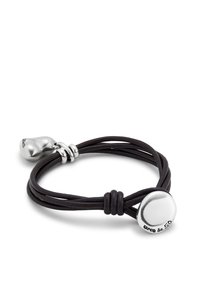 Pulsera de cuero negro con tres hebras, que cuenta con un cierre de disco de plata pulida y un acento redondeado de plata. Diseño simple y texturizado.