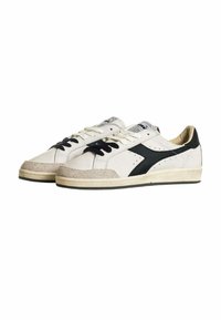 Sneakers bianchi in pelle con accenti neri, punta in suede color beige, design perforato e lacci neri. Silhouette classica di scarpa sportiva.