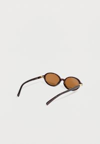 Γυαλιά ηλίου με καφέ φιμε φακούς σε στρογγυλό σχήμα, σκελετό χελώνας και μαύρα σκέλη με χρυσές λεπτομέρειες. Λεία υφή, ελαφρύς σχεδιασμός.