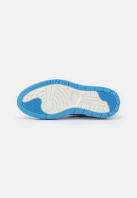 Nike shoe outsole featuring a blue rubber base with white accents, textured patterns, and a circular emblem in the heel area.