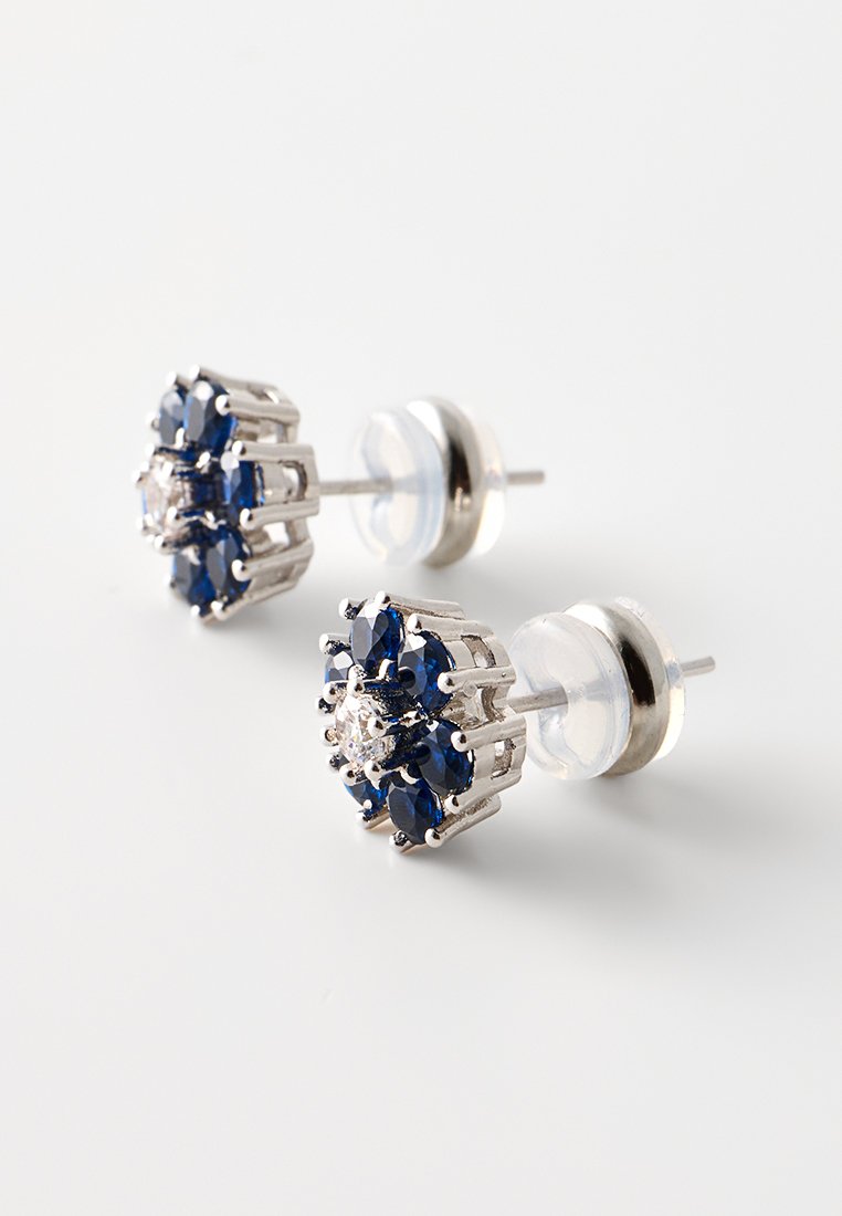 Silberfarbene Steckerohrringe mit floralem Design, verziert mit blauen Edelsteinen und einem zentralen klaren Stein, ergänzt durch klare Kunststoffrücken.