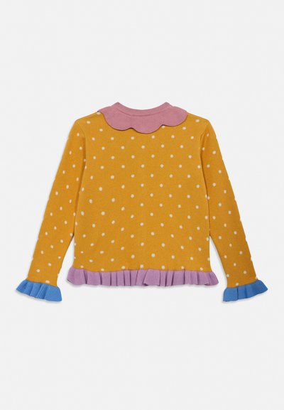 Pikad varrukad kollane kampsun valgete polka-täppidega, roosa laineline krae ja ääreosa ning sinised volangidega varrukaotsad valgel taustal.