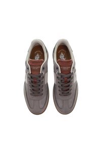 Šedé tenisky s kombinací kůže a textilu, s polstrovaným jazykem, hnědými tkaničkami a kontrastním bílým postranním panelem.