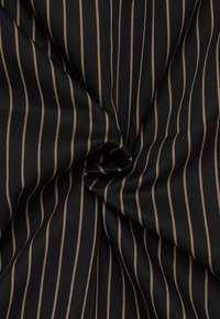 Tessuto nero con strette righe dorate, caratterizzato da una trama testurizzata e una leggera lucentezza, raccolto in un giro circolare.