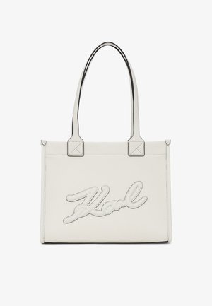 Fehér bőr tote táska fekete díszítéssel, a "Karl" logó dombornyomott mintájával, két fogantyúval és strukturált, téglalap alakú formával. Texturált felület.