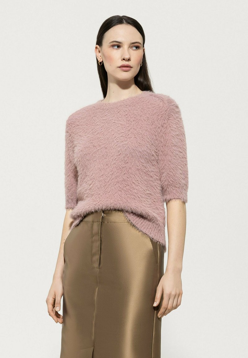 Pink fluffy short-sleeve sweater with a round neckline, paired with a satin gold skirt featuring a slit at the front.