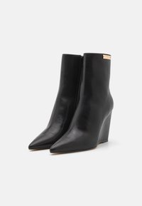 Black leather ankle boots with a wedge heel, pointed toe, and a side zipper. Features a metallic accent on the upper. Smooth texture.