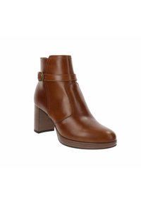Botte de cheville en cuir marron avec un bout rond, un détail de sangle sur le côté et un talon épais. Texture lisse et couture minimaliste.