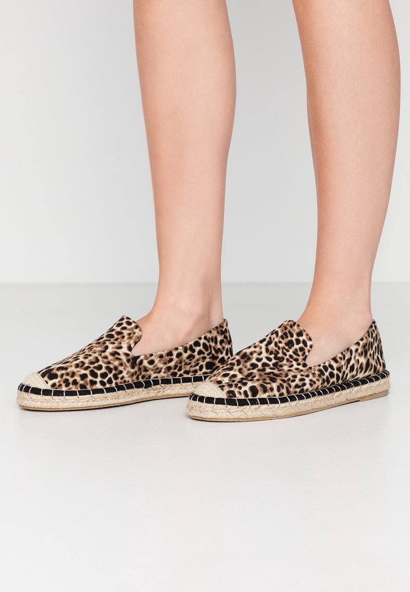 Espadrilles à imprimé léopard avec un design à enfiler, comprenant une tige en tissu texturé, une semelle extérieure en jute tressé et des accents noirs. Profil plat.