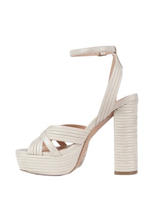 Sandalo beige con tacco alto, cinturini incrociati, cinturino alla caviglia, suola piattaforma e tacco spesso impilato con scanalature orizzontali.