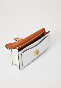 Vit läderclutch med prägling, inredning i tanmocka, guldfärgad dragkedja och magnetstängning. Öppnas brett för enkel åtkomst.
