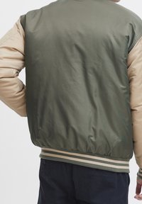 Reversible bomberjack met een olijfgroene buitenkant en beige mouwen, voorzien van ribgebreide boorden en zoom, gevoerde textuur en een casual ontwerp.