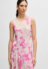Ärmelloses Kleid in hellbeige mit einem rosa abstrakten Blumenmuster. V-Ausschnitt-Design und strukturierten Stoff mit drapierten Details.