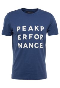 Modrá bavlněná tričko s velkými bílými blokovými písmeny, která na přední straně hlásají "PEAK PERFORMANCE". Klasický design s kulatým výstřihem.