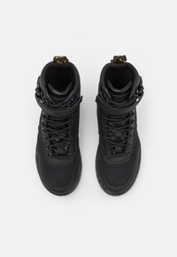 Baskets montantes noires avec une tige en mesh, un collier de cheville rembourré et un design à lacets avec une sangle. Branding discret et accents texturés.