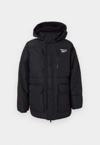 Jachetă izolată neagră cu glugă, având fermoar frontal, două buzunare cu fermoar pe piept și două buzunare mari în față. Logo-ul Reebok pe piept.