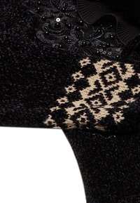 Calzature in tessuto nero con decorazioni di paillettes e dettagli in pizzo. Presentano un design a motivi beige e nero sul lato. Texture morbida.