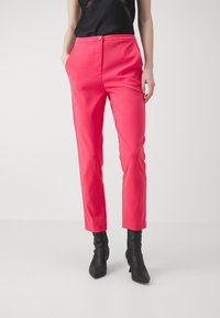 Fuksia muotihousut slim fit -tyyliin, joissa on sivutaskut ja litteä etumuksen. Yhdistetty mustiin nilkkureihin, korostaen modernia siluettia.