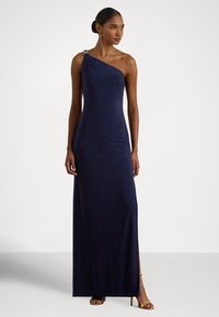 Granatowa, asymetryczna sukienka z gładkiej tkaniny z drapowanymi detalami, ozdobiona dekoracyjną klamrą na ramieniu i rozcięciem z boku.