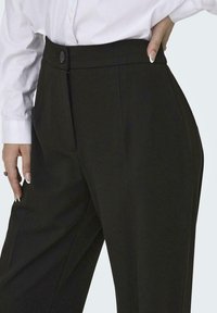 Hochtaillierte schwarze Hosen aus einem glatten, strukturierten Stoff mit einem vorderen Bundfalten, seitlichen Eingrifftaschen und einem knopfartigen Verschluss.